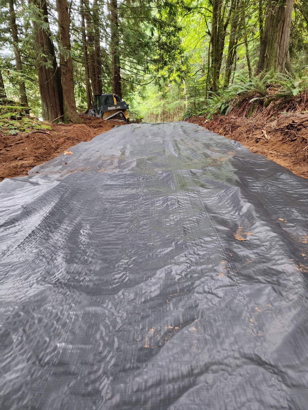 Geotextile fabric laid over a cut road bed before gravel