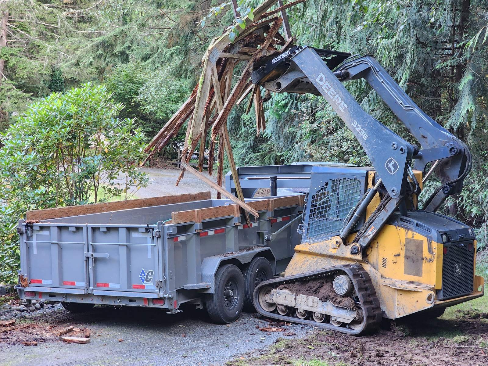 Track loader loading broken wood debris into a dump trailer