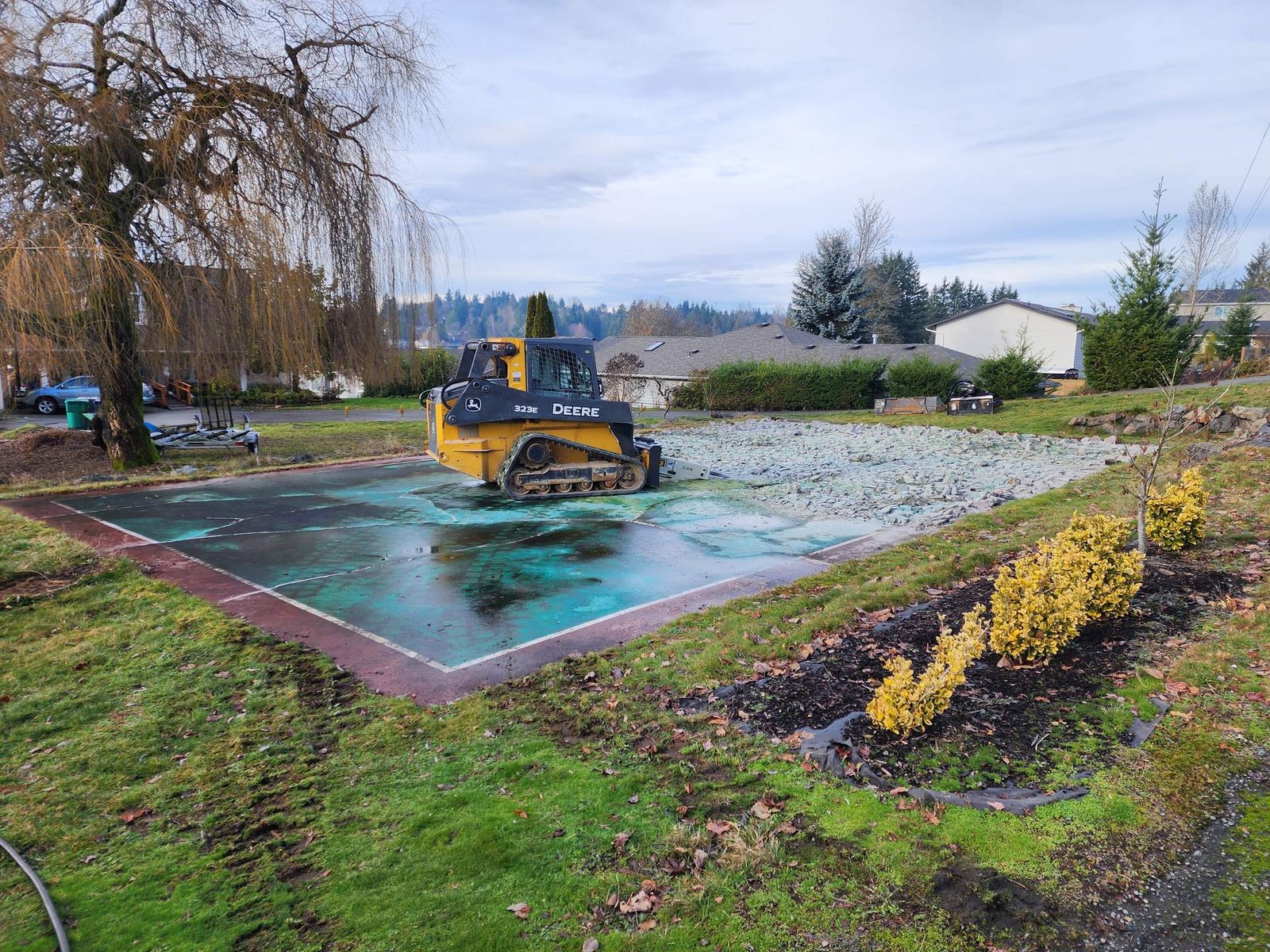 Compact track loader breaking up and removing an old concrete sport court
