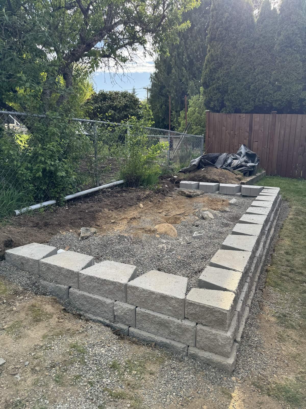 Short stacked concrete block retaining wall around a leveled gravel area